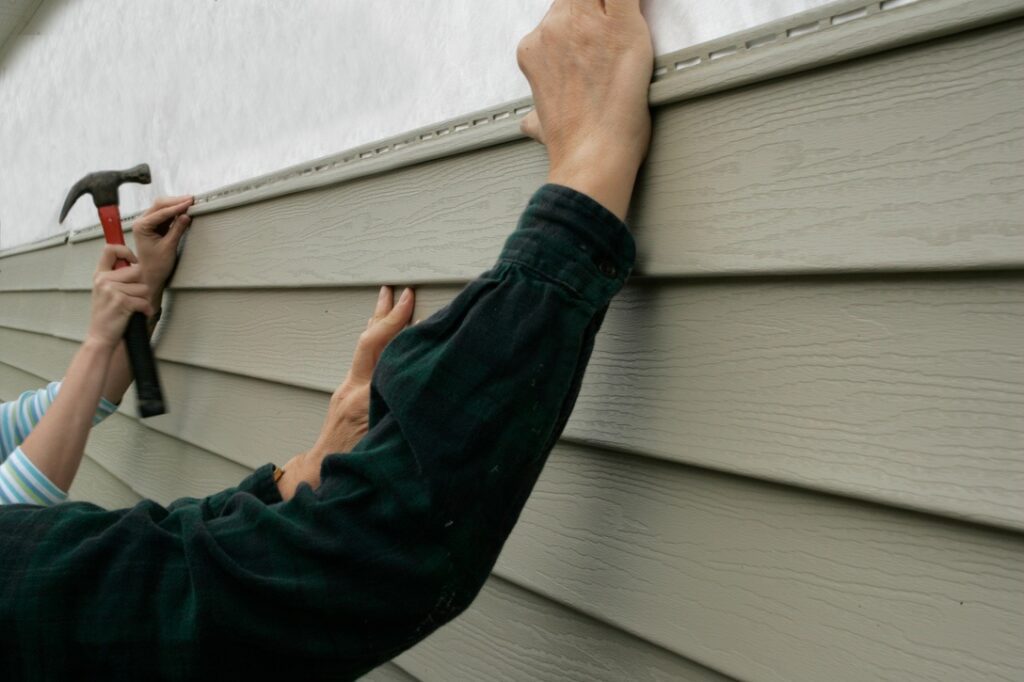 People putting siding on home in accordance with architectural controls Workers installing siding on a house